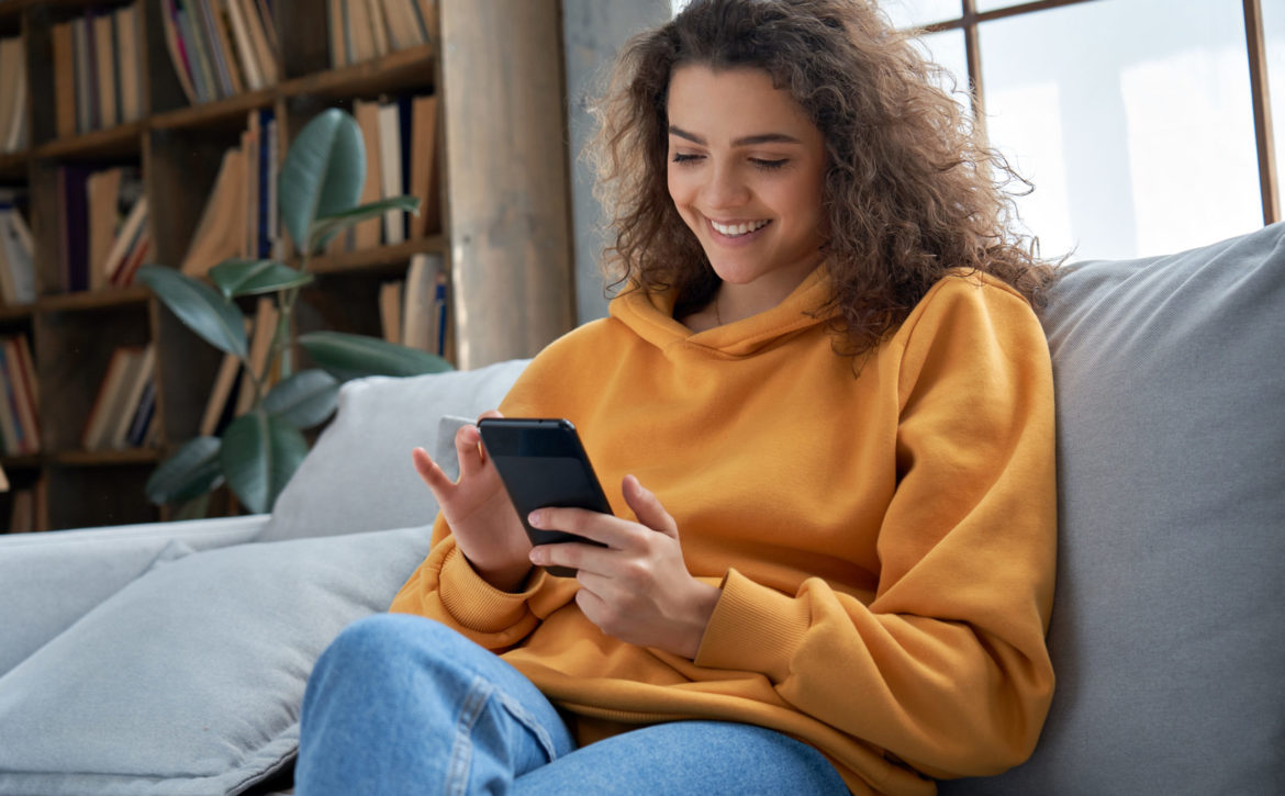 Happy,Millennial,Hispanic,Teen,Girl,Checking,Social,Media,Holding,Smartphone
