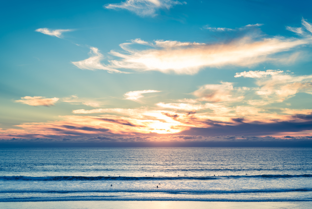 A,Colorful,California,Sunset,Behind,An,Ocean,Filled,With,Surfers